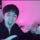 a man is making a funny face with his mouth open in front of a pink background .