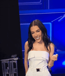a woman in a white dress is smiling while giving the middle finger