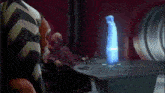 a group of people are sitting around a table with a hologram of a person coming out of the table .