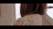 a woman in a white lace dress is looking at herself in the mirror .