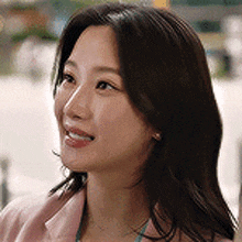 a close up of a woman 's face with long hair wearing a pink jacket .