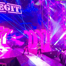 a woman stands on a stage in front of a large sign that says legit