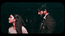 a man and a woman are standing next to each other in a dark room and looking at each other .