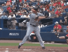 a baseball player is swinging at a ball in front of a fs south sign