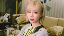a woman with short blonde hair is sitting on a couch and looking at the camera