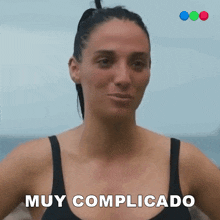 a woman in a black tank top says muy complicado in white letters