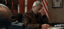 a man sitting at a desk with a netflix logo on the bottom right