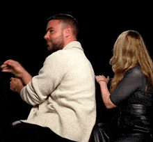 a man and a woman are sitting back to back with their hands in the air .