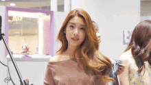 a woman in a pink off the shoulder top stands in front of a microphone