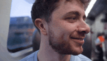 a man with a beard is smiling and looking out the window