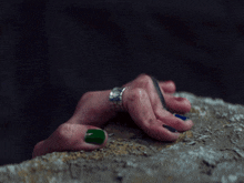 a woman 's hand with green nails and a silver ring on her finger