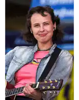a woman in a pink shirt is holding a guitar with the brand name fender on it