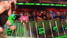 a crowd of people watching a wrestling match in a stadium with a sign that says ' wwe ' on it .