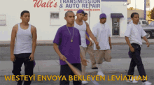 a group of young men are walking down a sidewalk in front of a walt 's transmission and auto repair store