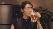 a woman drinking a glass of beer with a sticker that says ' lg '