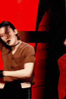 a man wearing a choker is dancing in front of a red wall