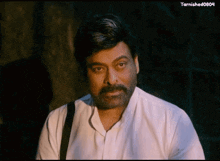 a man with a beard is wearing a white shirt and a black strap around his neck .