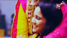 a woman in a pink and yellow dress is smiling in front of a sign that says sony