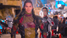a man with long hair is walking down a street with another man