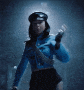 a woman in a blue jacket and hat holds a gun