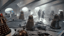 a man and a woman stand in a room surrounded by daleks