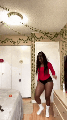 a woman in a red top and black shorts is dancing