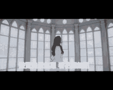 a woman in a white dress stands in a room with chinese writing on the bottom