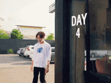 a man walking in front of a building that says day 4 on it
