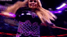 a woman in a black and purple dress is holding a hula hoop in her hands .