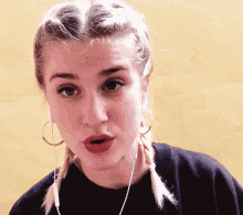 a woman wearing braids and hoop earrings is making a face