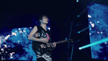 a man playing a guitar in front of a large screen that says ' d ' on it