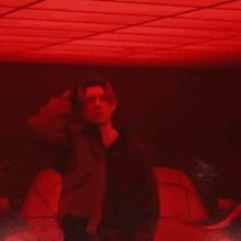 a man is standing in a dark room with a red light shining on his face .