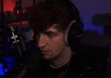 a man wearing headphones and a watch is sitting in front of a microphone in a dark room .