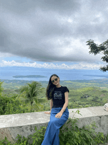 a woman sitting on a wall with a view of a body of water behind her