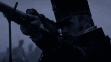 a man in a black hat is holding a gun in his right hand