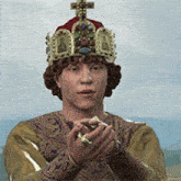 a man with a crown on his head is holding a ring in his hands