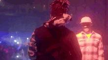 a man in a hoodie is standing next to another man in a plaid shirt .