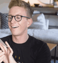 a man wearing glasses and a black shirt is looking at his phone