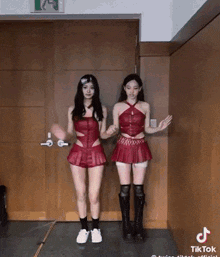 two women in red skirts are dancing in front of a door with a sign that says exit