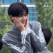 a man in a grey jacket with white stripes on the sleeves is smiling