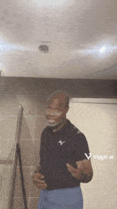 a man in a black shirt and blue shorts is standing in a bathroom with a viggle.com logo