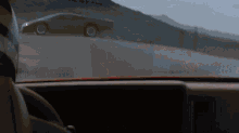 a car is driving down a road with mountains behind it