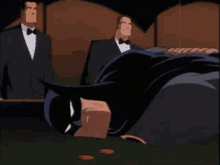 a man in a tuxedo stands behind a man in a batman suit