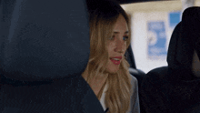 a woman is sitting in the back seat of a car with her eyes closed .