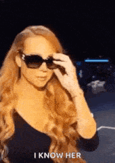 a woman with long red hair is wearing sunglasses and a black top .