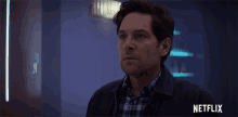 a man in a plaid shirt is standing in front of a netflix ad