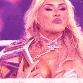 a woman with blonde hair is wearing a purple choker and holding a championship belt