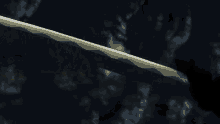 a person is standing in the dark with a sword in their hand and a light coming out of the ground .