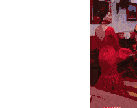a woman in a red dress is dancing with a man in a white shirt in a room .
