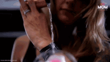 a woman with a ring on her finger is drinking from a glass with the word mom on the bottom